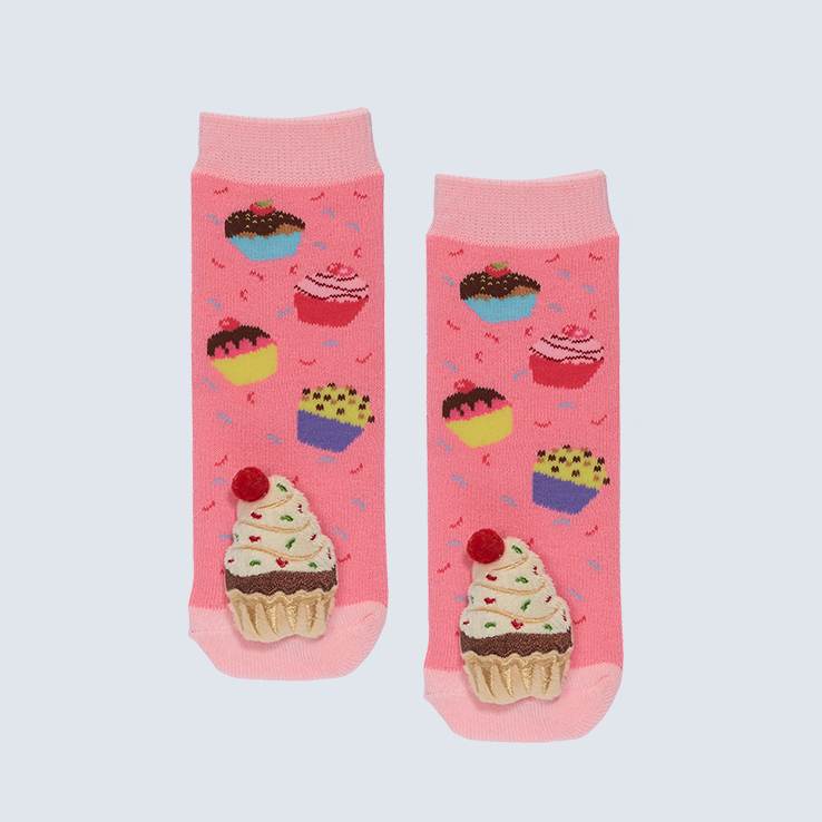 Two socks against a white background. The socks feature cupcakes and a cute plush on each toe.