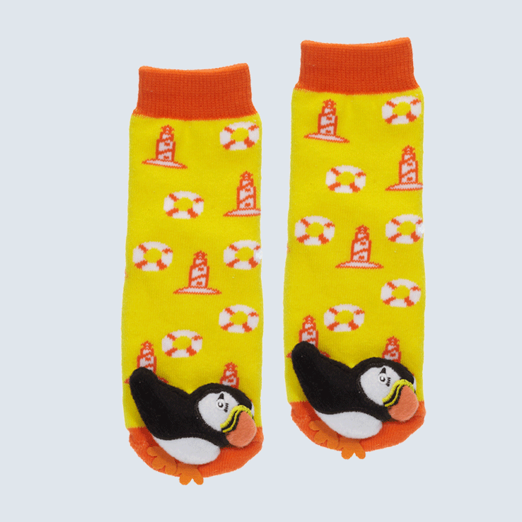 Two yellow and orange socks against a white background. The socks feature a lighthouse motif and a cute plush puffin charm on the toe.