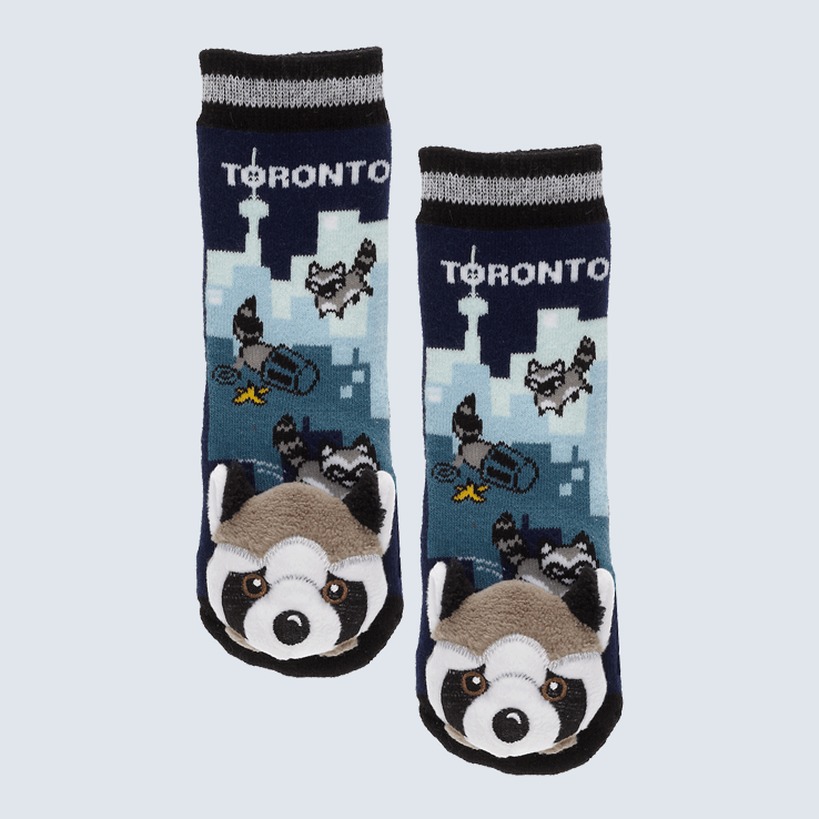 Two socks against a white background. The socks feature a Toronto skyline and a cute plush raccoon charm on the toe.